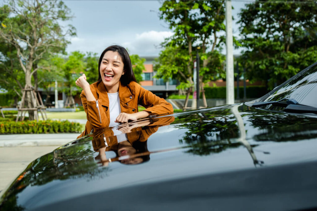 車の前で喜んでいる女性