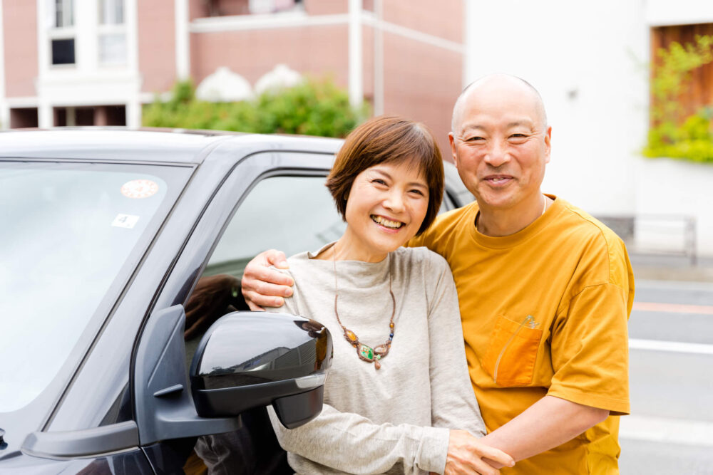 車の前で肩を寄せている男女